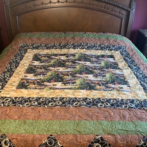 May include: A brown, green, and black quilt with a pattern of rope circles and a central panel featuring a herd of horses in a field.