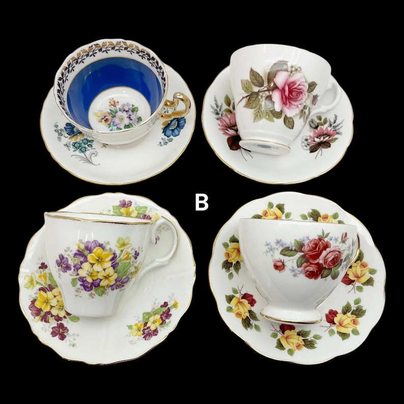 May include: Four vintage teacups and saucers are displayed against a black background. The teacups feature floral designs and gold trim. One cup has a blue interior, while others showcase pink, red, and yellow roses and other flowers.