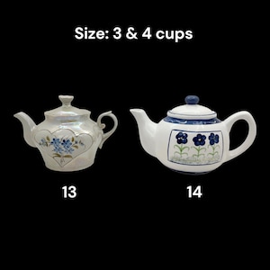 May include: Two ceramic teapots. One is iridescent with blue floral accents and a heart design. The other is white with blue floral patterns and trim. The text "Size: 3 & 4 cups" is at the top. Numbers 13 and 14 are at the bottom.