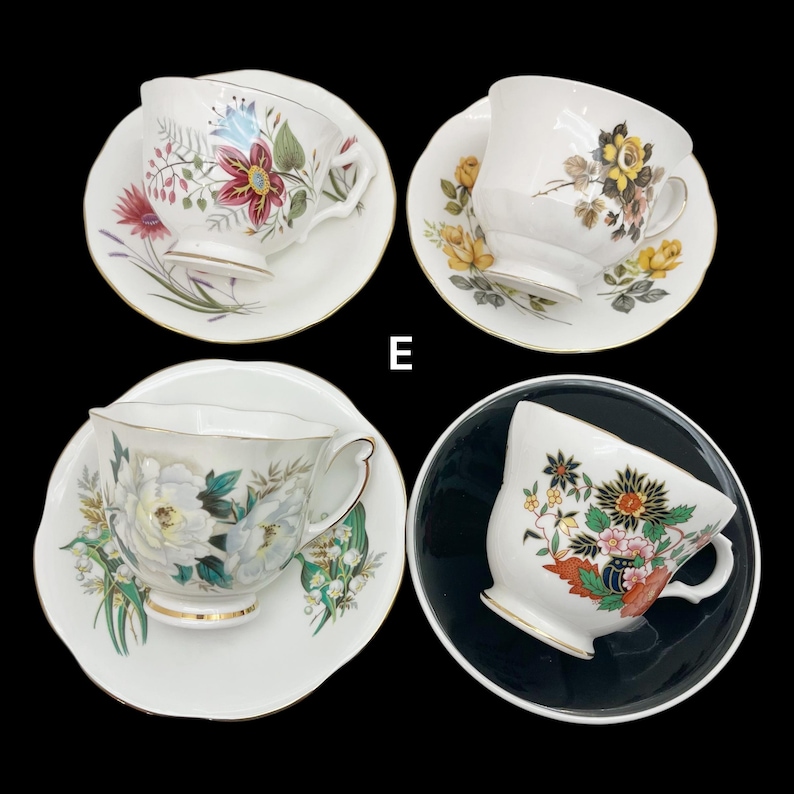 May include: Four vintage teacups and saucers with floral designs. The teacups feature various patterns, including red, yellow, and white flowers. Each cup and saucer has a gold trim. The background is black.