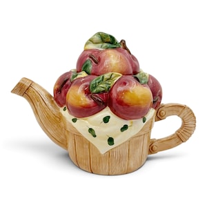 Peut inclure: Une théière en céramique en forme de panier tressé rempli de pommes rouges et jaunes. Le couvercle présente un groupe de pommes avec des feuilles vertes, tandis que la base ressemble à un panier en bois clair avec un tissu crème drapé dessus.