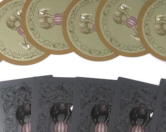 May include: A set of seven playing cards featuring a black and white illustration of an elephant balancing a ball on its trunk. The cards are arranged in a row, with the top card facing up and the rest facing down.