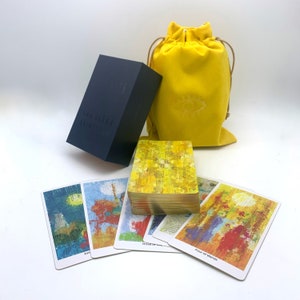 May include: A deck of tarot cards with a yellow and gold design. The cards are in a blue box with the words "Light Workers" on the front. The cards are also in a yellow velvet bag with a white symbol on the front.