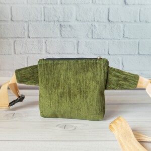 May include: A green corduroy fanny pack with a zipper closure and a beige adjustable strap.