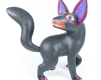 May include: A black wooden carved animal figurine with purple and pink painted ears and details. The figurine has a long tail and is standing on all fours.