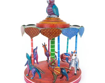 May include: A colourful wooden carousel with a parrot on top and various animals, including a deer, a cat, and an elephant, painted in bright colours.