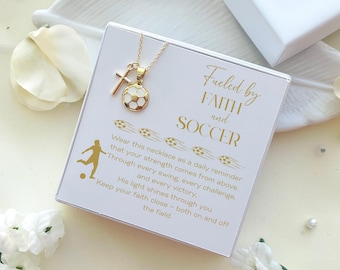 Könnte beinhalten: Goldfarbene Halskette mit einem Fußballanhänger und einem Kreuz. Präsentiert in einer weißen Schachtel mit dem goldenen Schriftzug "Fueled by Faith and Soccer". Die Schachtel enthält auch eine motivierende Botschaft.