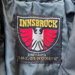 May include: Black and red patch with white stitching. The patch has a white eagle with red wings and the text "INNSBRUCK" in yellow letters. The text "styled in Austria" and "GR.44, XL-US 16-OW 101CM-BUST 40" is also on the patch.