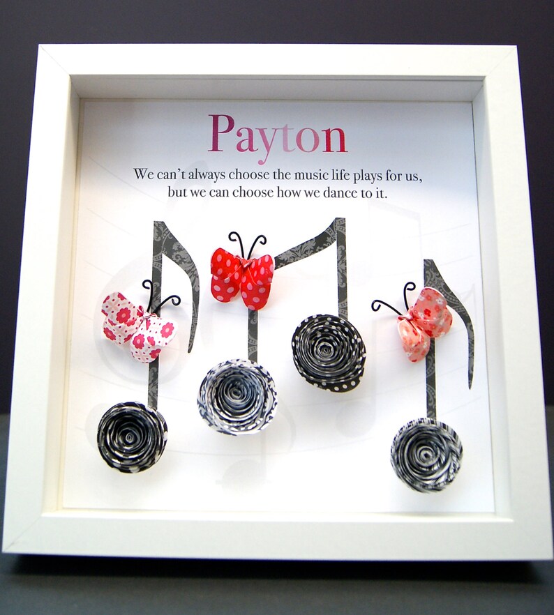 May include: A white framed picture with the name "Payton" at the top. The picture features a quote about music and life, and is decorated with paper butterflies and musical notes.