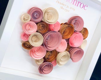 May include: A framed shadow box containing a heart-shaped arrangement of rolled paper flowers in shades of pink, cream, and copper. The white background features the printed text Monroe, October 31, 2019, and 7lbs 15oz in pink and gold.