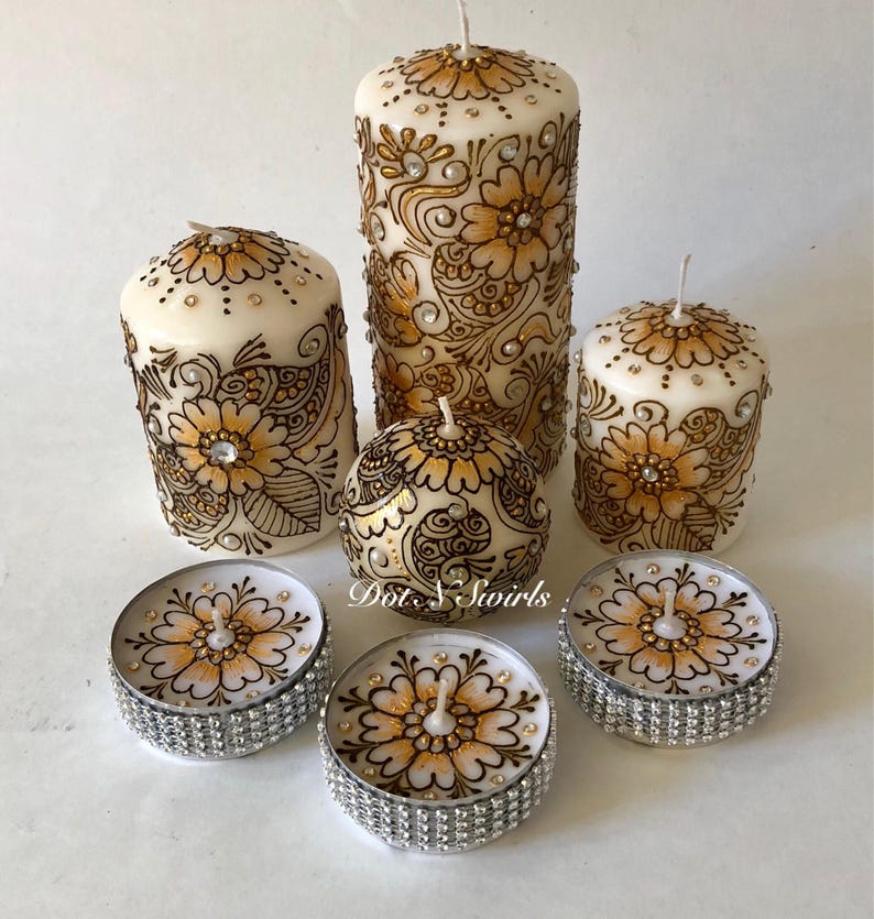 Puede incluir: Conjunto de seis velas con intrincados dise&ntilde;os de henna dorados y pedrer&iacute;a. El conjunto incluye tres velas pilares y tres velas de t&eacute;.