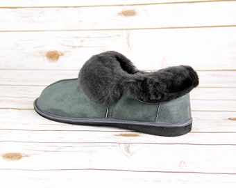 May include: Gray suede slipper with a black faux fur trim around the top. The slipper has a black rubber sole.