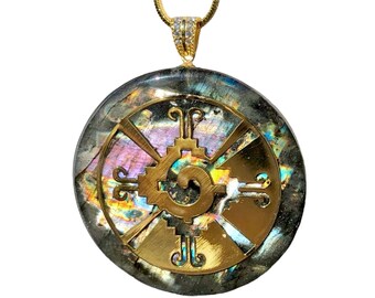 May include: A gold pendant necklace with a round, iridescent labradorite stone featuring a gold Aztec calendar symbol.