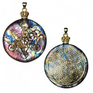 May include: Two round pendants with gold-colored crowns and bails. One pendant features a gold Metatron's Cube design, the other a Flower of Life. The pendants have a shimmering, iridescent background with purple, blue, and gold hues.