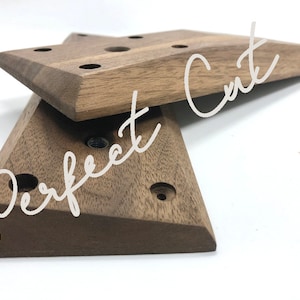 May include: Two wooden star-shaped pieces with multiple holes drilled into them. The pieces are stacked on top of each other. The top piece is slightly larger than the bottom piece. The wood is a dark brown colour.