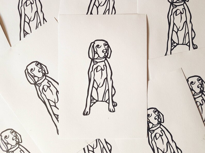 May include: A collection of white cards featuring a black line drawing of a dog in a seated position. The dog has a collar and is depicted with simple, bold lines. The cards are scattered, with some partially visible.