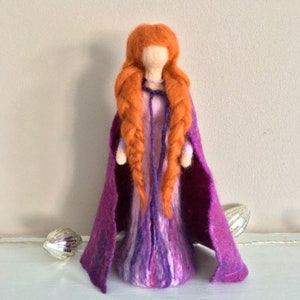 May include: A felt doll with long braided red hair, wearing a purple dress and a matching cape.