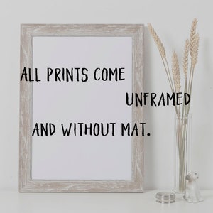 May include: A framed white print with the text "ALL PRINTS COME UNFRAMED AND WITHOUT MAT." The frame is a light, weathered wood color. A clear glass vase with wheat stalks and a small decorative dog figurine are to the right.
