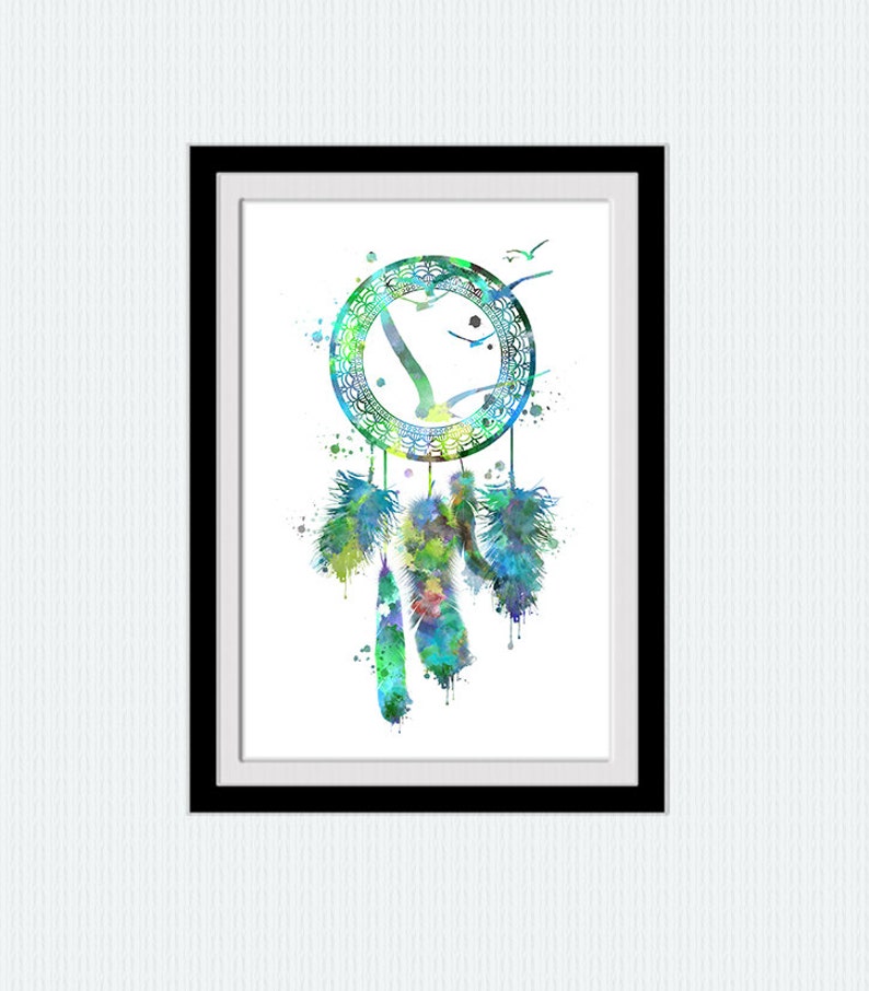 May include: Watercolor painting of a dreamcatcher in a black frame. The dreamcatcher is a circle with a web design, birds, and feathers in shades of blue, green, and yellow. The artwork is on a white background.
