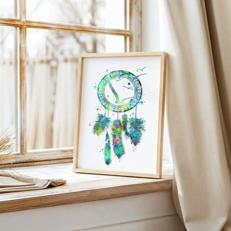 May include: A framed watercolor print of a dreamcatcher. The dreamcatcher is depicted with a circular design in shades of green and blue, with feathers hanging below. The artwork is displayed in a wooden frame.