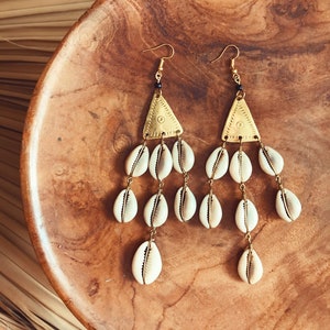 May include: Gold tone earrings with a triangular pendant and multiple white shell charms hanging from the bottom.