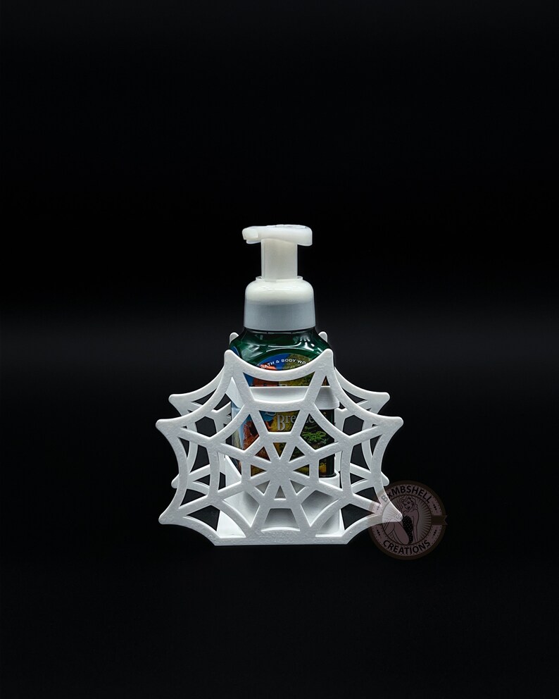May include: White plastic spiderweb soap dispenser holder. The holder is shaped like a spiderweb and has a small opening in the center for the soap dispenser to fit through. The soap dispenser is not included.