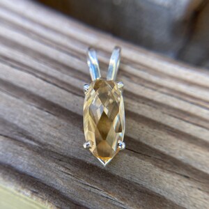 Op de afbeelding: Een zilveren hanger met een lichtbruine, gefacetteerde edelsteen. De edelsteen heeft een marquise-vorm.