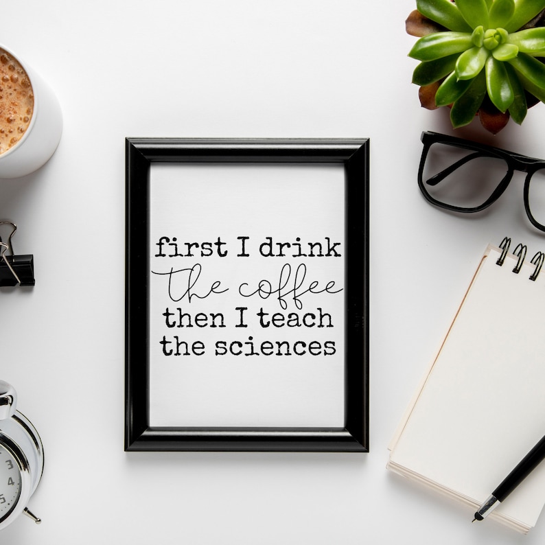 May include: Black framed print with the text "first I drink the coffee then I teach the sciences" on a white background. The print is on a white surface with a coffee cup, a notebook, a pen, and a succulent plant.