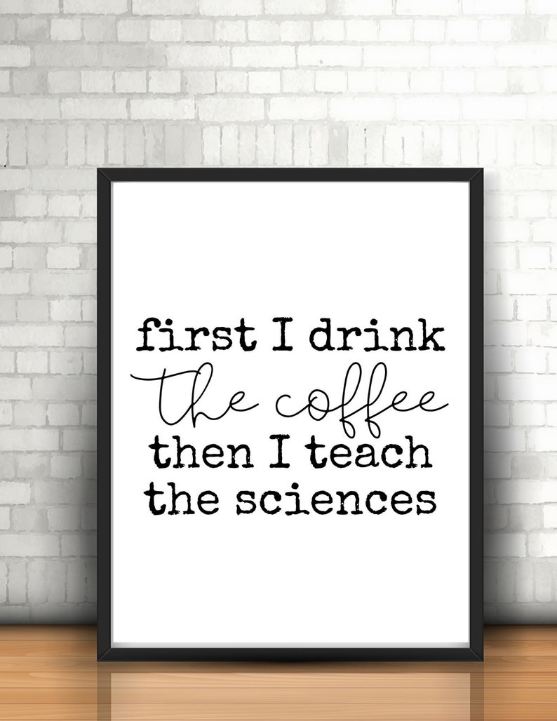 May include: Black and white typography print with the text "first I drink the coffee then I teach the sciences". The print is framed in a black frame and is displayed against a white brick wall.
