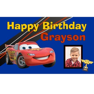 May include: A blue banner with the text "Happy Birthday Grayson" in yellow and red letters. A red cartoon race car is on the left side of the banner. A photo of a young boy is on the right side of the banner.