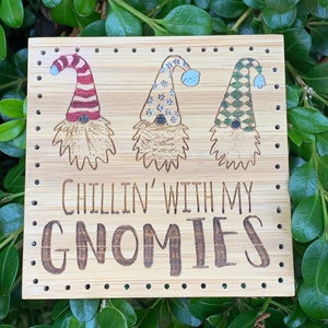 May include: A bamboo sign featuring three gnome illustrations with different hat patterns: red and white stripes, blue stars, and green diamonds. The sign reads "Chillin' With My Gnomies" in a carved font, perfect for home decor.