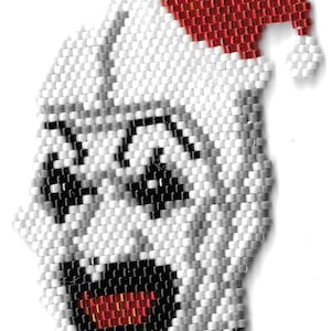 May include: A white beaded ornament of a face with a red Santa hat. The face has black eyes, a black mouth, and a red nose.