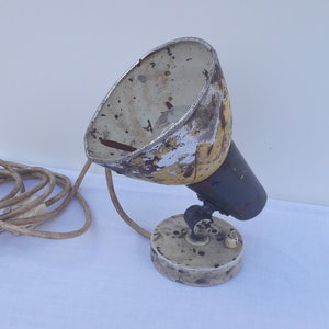 May include: A vintage yellow and white metal lamp with a black base and a coiled cord. The lamp has a simple design and is in good condition.