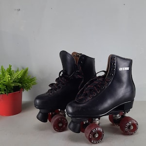May include: A pair of black roller skates with red wheels. The wheels have the word "OTRS" printed on them.