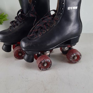 May include: A pair of black roller skates with red wheels. The skates have black laces and the word "OTRS" is printed on the side of the right skate.