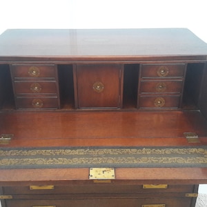 May include: A mahogany antique secretary desk with brass hardware. The desk has a drop-down front with a leather writing surface and a series of drawers above and below.