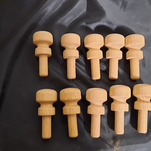 May include: Twelve wooden knobs with a rounded top and a cylindrical base. The knobs are arranged in two rows of six.
