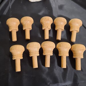 May include: Ten wooden knobs with a rounded top and a cylindrical stem. The knobs are a light brown colour and have a smooth finish.