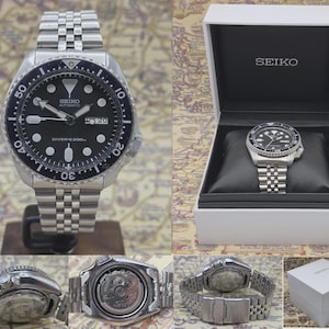 Può includere: Un orologio subacqueo automatico Seiko in acciaio inossidabile con quadrante nero, indici luminescenti e datario. L'orologio ha una lunetta girevole e un bracciale in acciaio inossidabile. L'orologio è esposto nella sua scatola bianca originale.