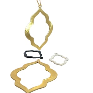 May include: Three gold-colored metal pendant charms in the shape of a quatrefoil. The charms are different sizes and have a textured surface.