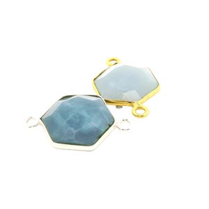 May include: Two hexagonal gemstone connectors. One has a silver-colored bezel and a blue-green stone. The other has a gold-colored bezel and a light blue stone. Both have small loops for attaching to other components.