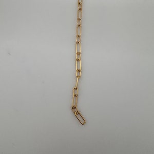 Könnte beinhalten: Eine goldene Kettenkette mit einem einfachen, verlinkten Design.