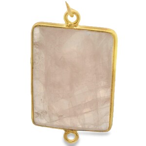 Pode incluir: Um pingente retangular com uma pedra rosa pálido emoldurada em ouro. A pedra tem uma aparência translúcida com padrões internos sutis. O pingente tem uma argola na parte superior e inferior para fixação.