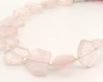 May include: A necklace featuring irregular, faceted rose quartz beads strung on a silver wire. The beads are a soft pink color. The necklace ends with a pink tassel and silver accents.