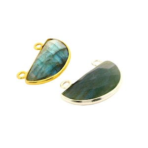 May include: Two half-moon shaped labradorite gemstone pendants. One is set in a gold-colored bezel, the other in silver. Each has two small loops for attaching to a chain or other jewelry component. The gemstones have blue and green iridescent colors.