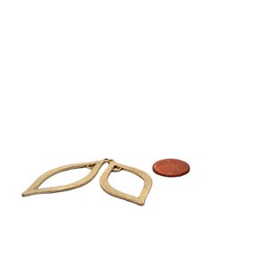 May include: Two gold leaf-shaped metal earrings with a textured surface. The earrings are about the size of a US penny.