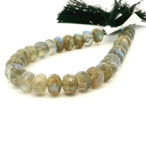May include: A strand of faceted labradorite beads in shades of gray, tan, and blue. The beads are strung together, with a dark green tassel at the top. The beads have a polished, iridescent appearance.