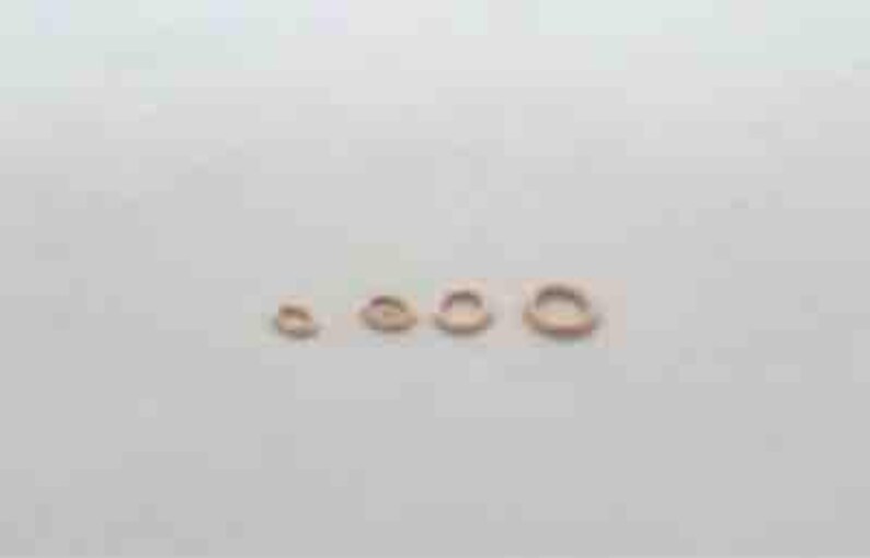 May include: Five gold jump rings of different sizes, arranged in a row from smallest to largest.