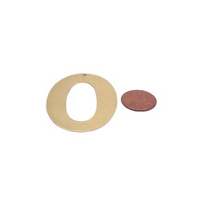 May include: A gold-colored metal letter O cutout, approximately the size of a US penny.