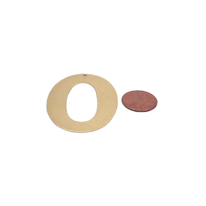May include: A gold-colored metal letter O cutout, approximately the size of a US penny.